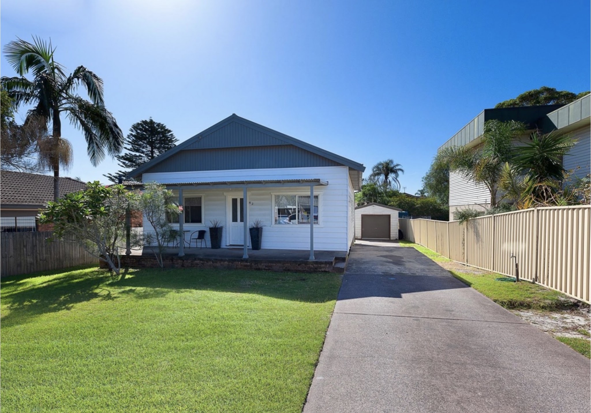 White weatherboard cottage with grey gable and front verandah