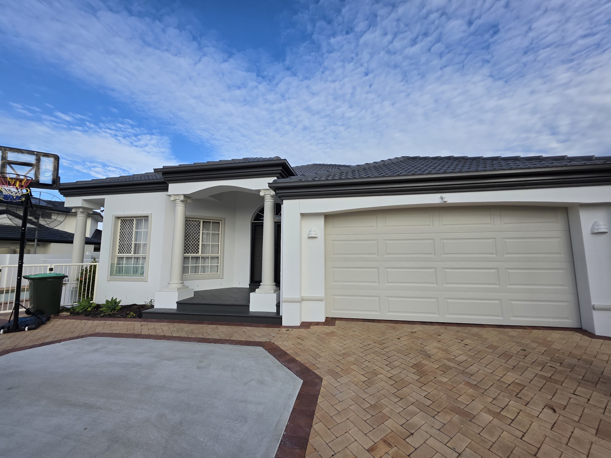 Rendered brick home in white with dark eaves and columns at the entry