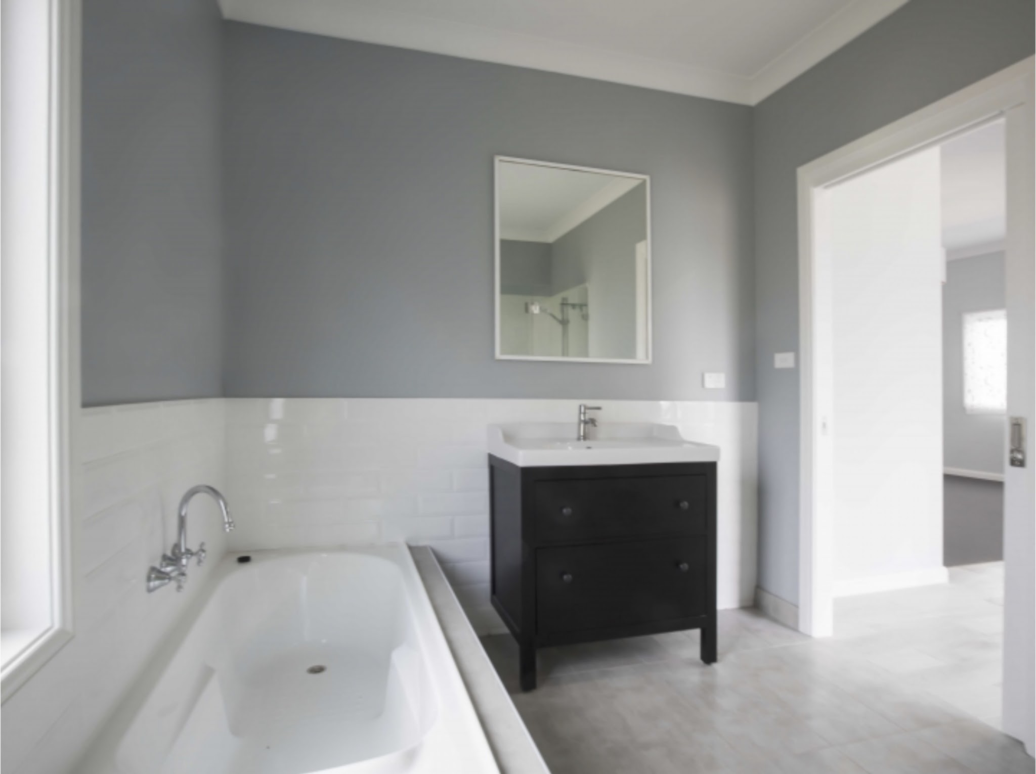 Bathroom with mid-grey feature walls above white subway tiles and a dark timber vanity