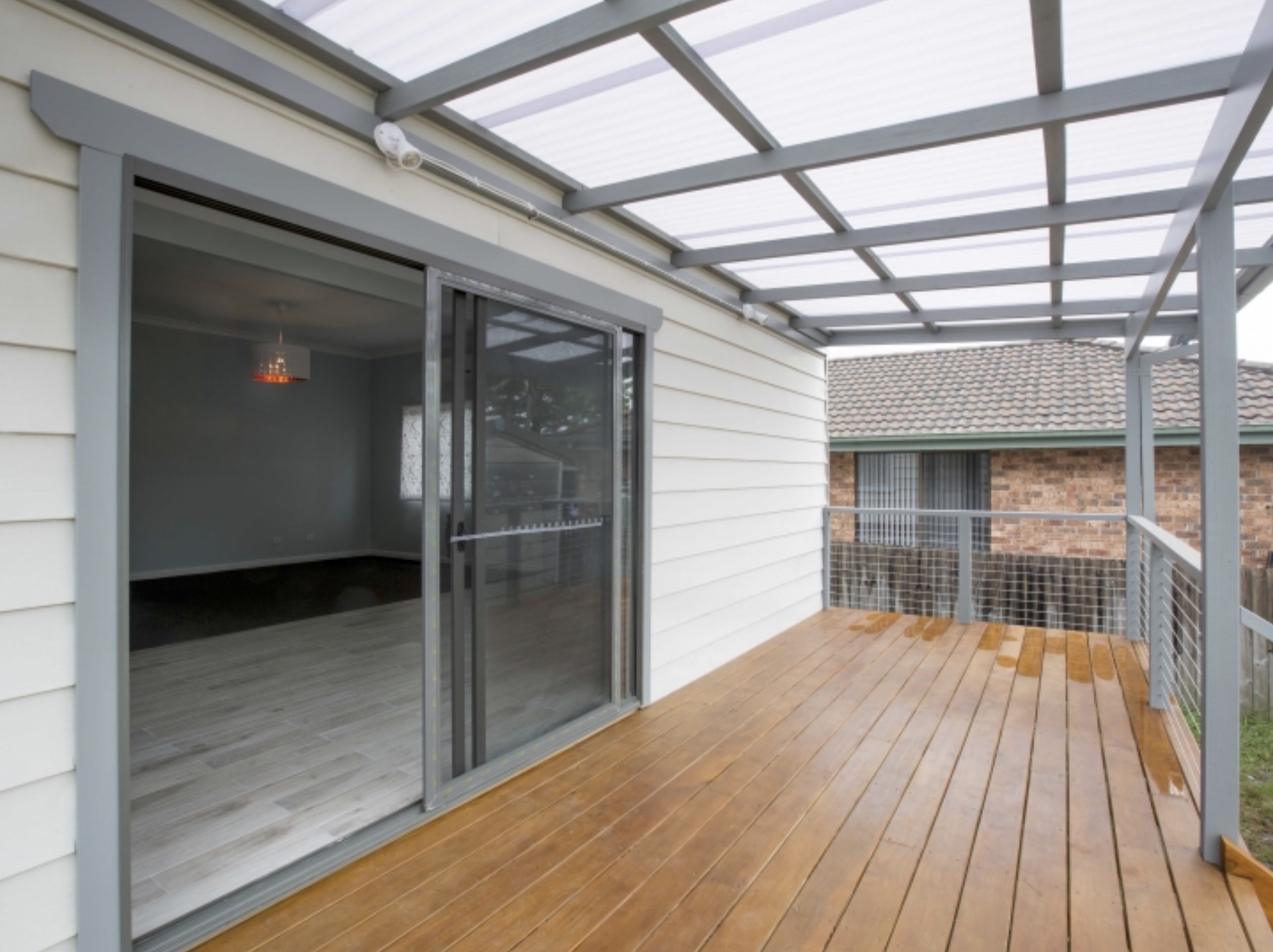 Back deck with pergola, grey-trimmed sliding doors and cream weatherboard