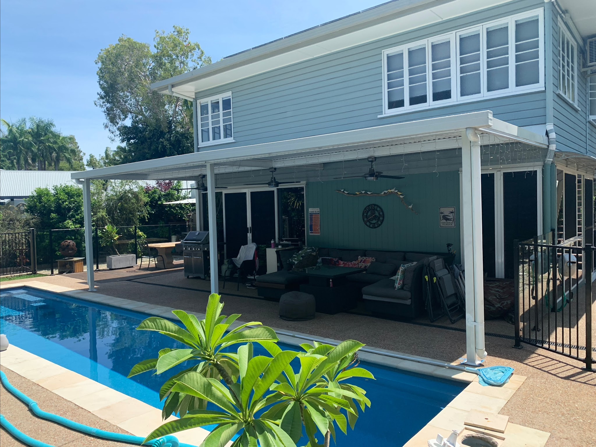 Blue-grey weatherboard home seen from the patio with a deep teal feature wall