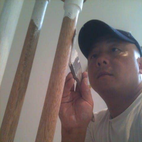 Gary brushing white paint onto timber stair spindles